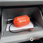 Öppet handskfack med den orange förvaringspåsen och visselpipan, en ficklampa, en isskrapa och ett vitt papper