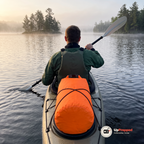 Kajakpaddlare sedd bakifrån med en orange drybag surrad på kajakens akterdäck