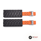 Ett par hjulbroddar: två svarta block med upphöjda klackar och varsin orange rem med silverfärgat spänne, packshot