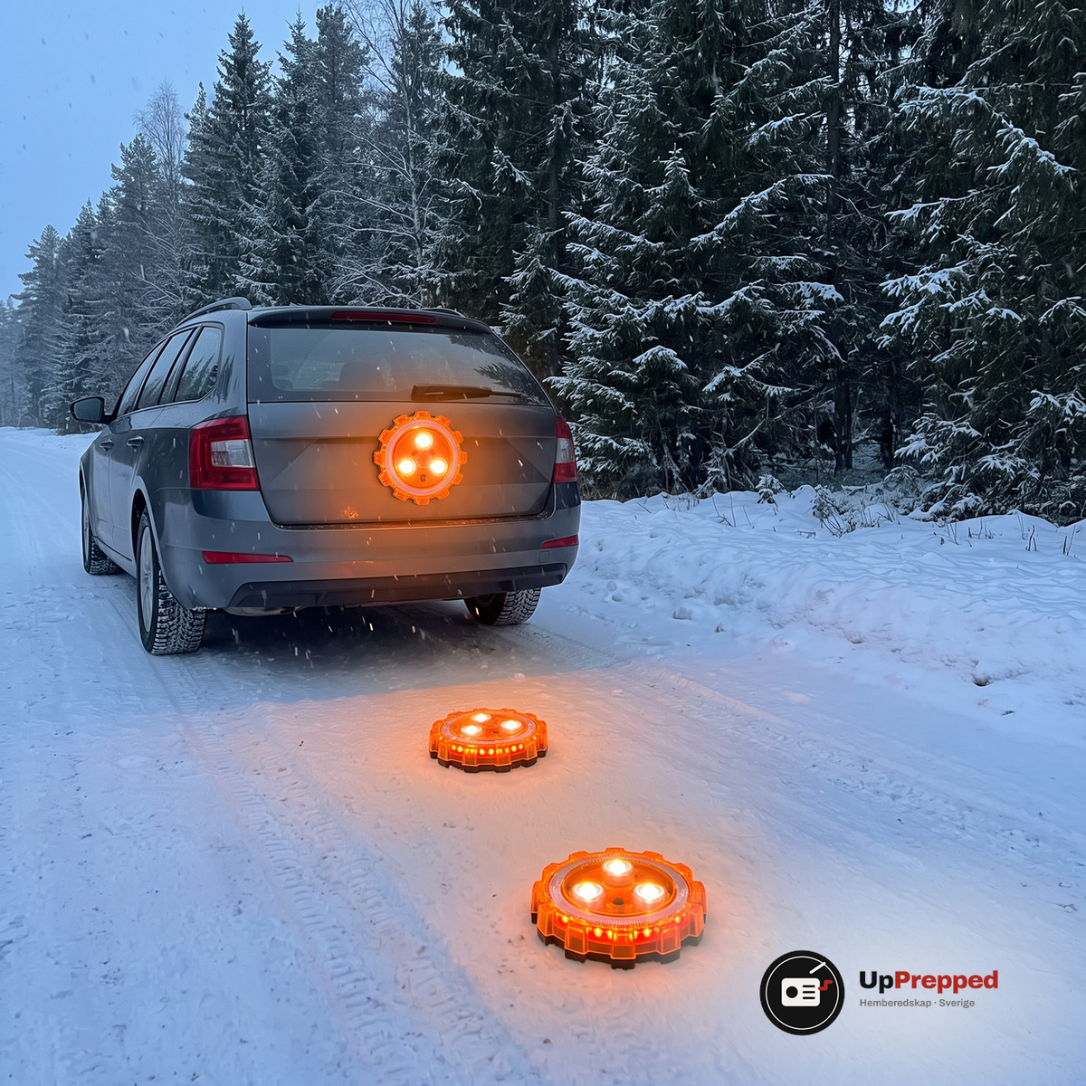 Tre orange LED varningsljus lyser, ett fäst på bagageluckan och två på den snöiga vägen bakom en kombi i skymningen