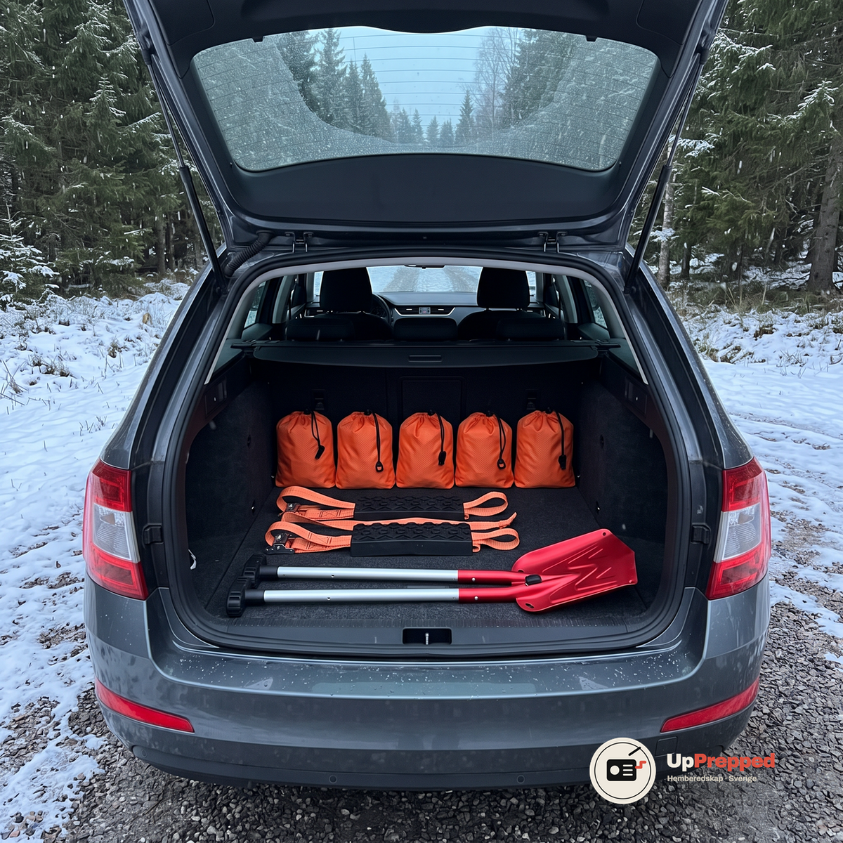 Fem orange förvaringspåsar, två hjulbroddar och två röda teleskopiska snöskyfflar utlagda i det öppna bagageutrymmet på en kombi vid en snöig skogsväg
