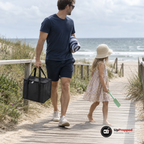 Pappa bär den lilla svarta kylbagen i handtagen längs en brygga mot stranden, dottern går bredvid med en spade