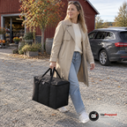 Kvinna bär den stora svarta kylbagen i handtagen över en grusplan utanför en gårdsbutik