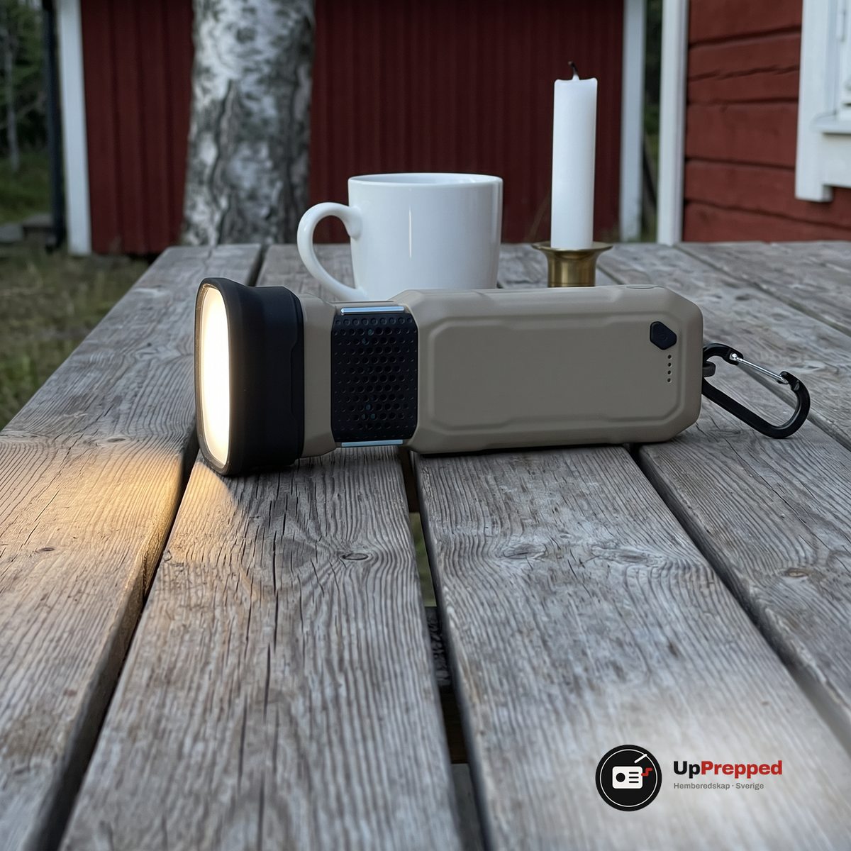Tänd dosa ligger på ett träbord på en veranda i skymningen bredvid en mugg och ett ljus