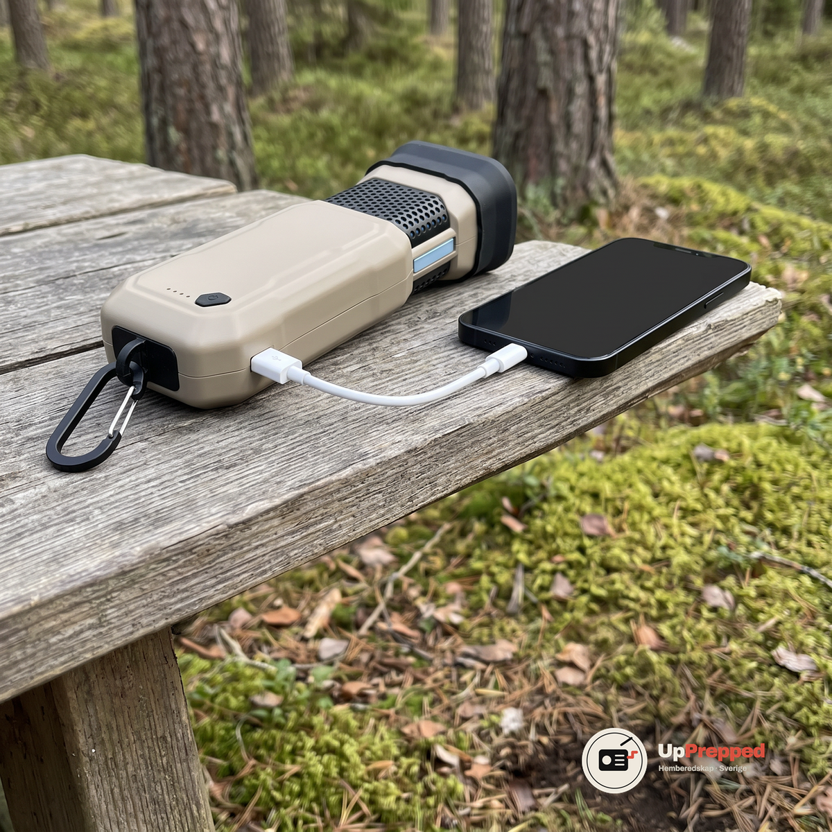 Dosan ligger på ett träbord i skogen med en USB-kabel kopplad till en mobil