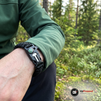 Närbild på armband med kompass i spännet på en handled i skogen