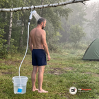 Man duschar under duschhuvudet som hänger i hållarens krok på en björkgren vid ett tält