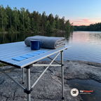Fem ljusblå refillmattor på ett hopfällbart campingbord vid en sjö i skymningen