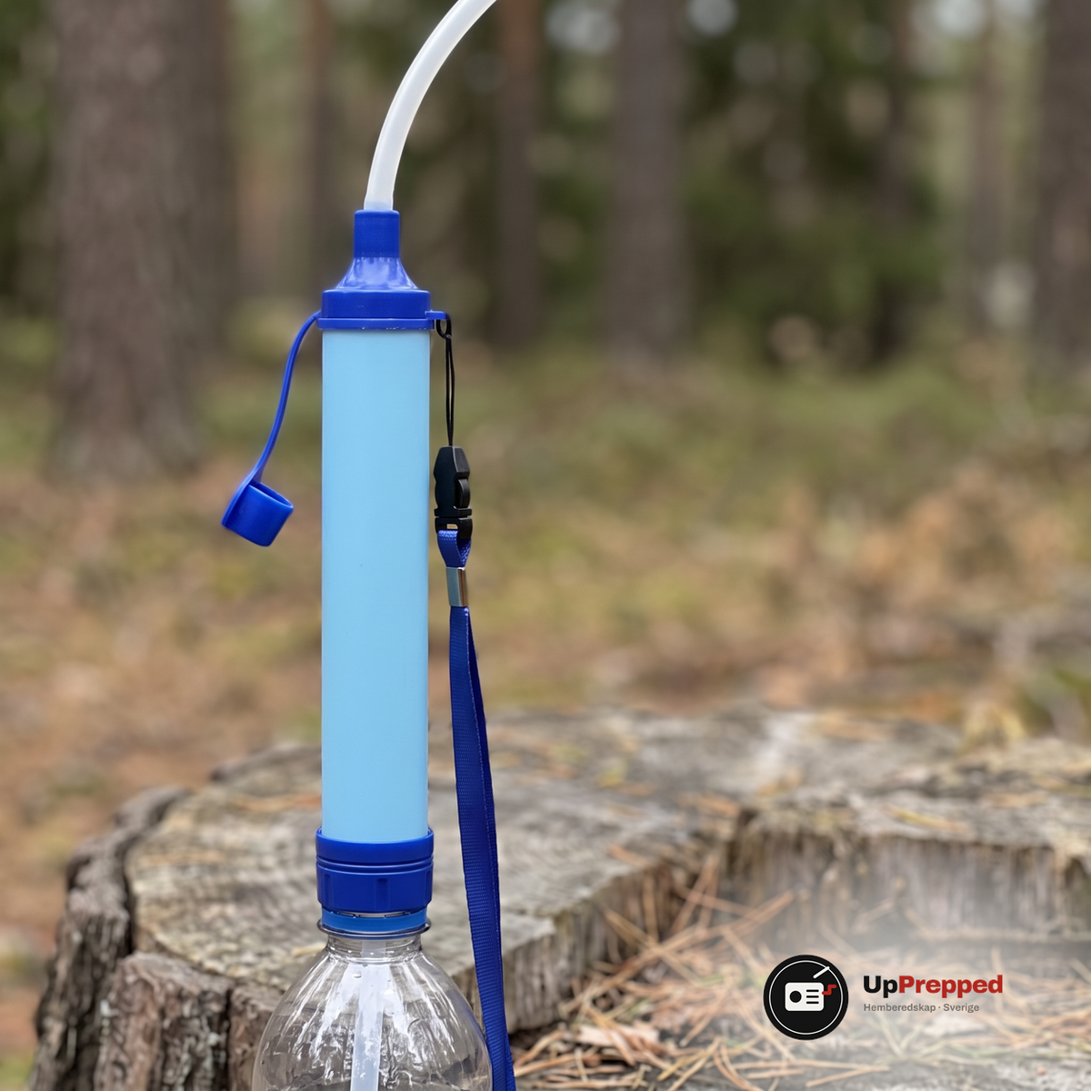 Närbild på det ljusblå filtret med slangen på toppen och bärbandet, på en stubbe i skogen