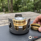 Närbild på plattan med trådhandtag på brännaren, med locket bredvid på ett skifferunderlag