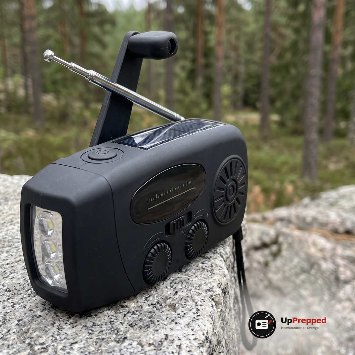 Närbild på nödradions vev, antenn och solpanel på en granithäll i skogen