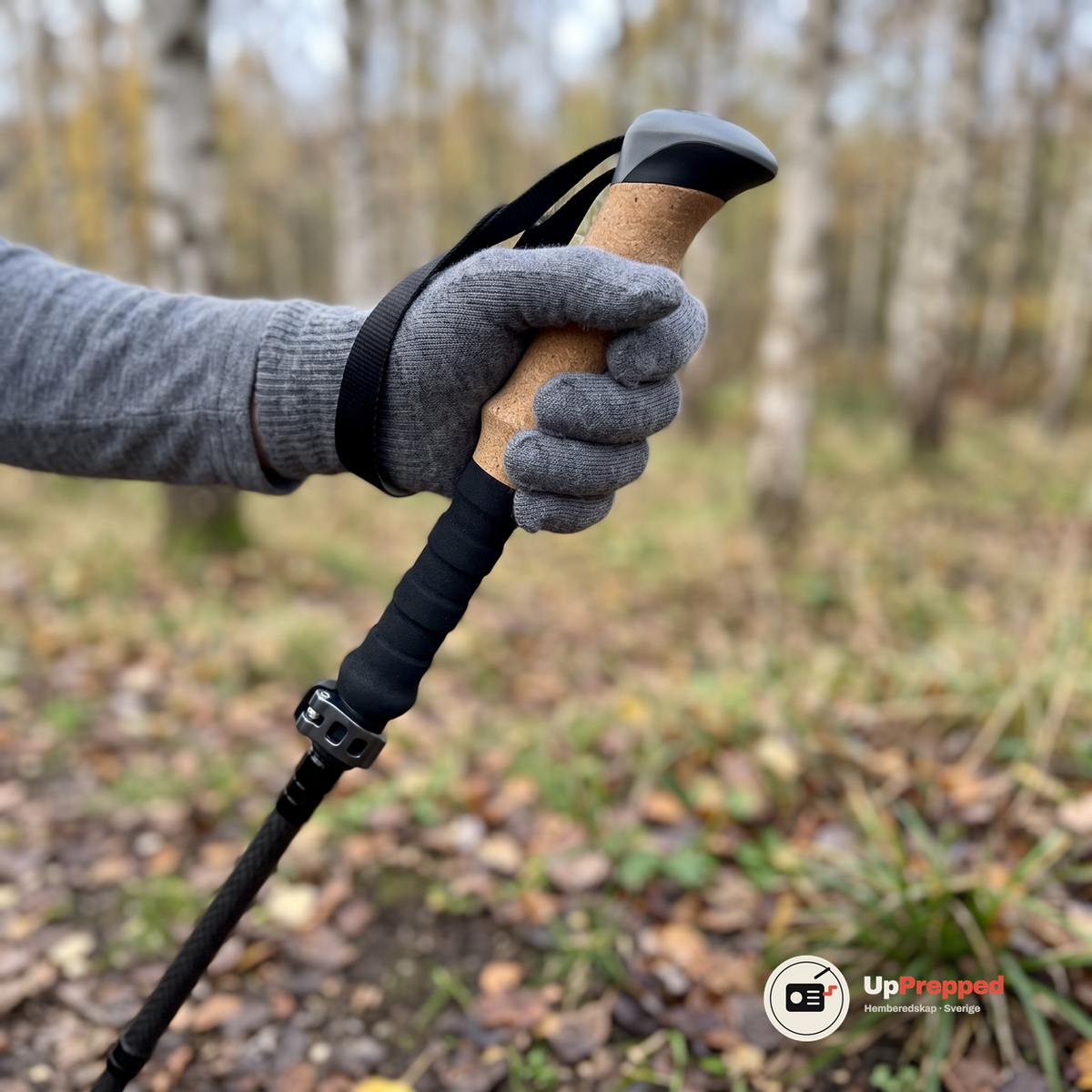 Hand i grå ullhandske håller i en vandringsstavs korkhandtag med skum nedtill och handledsrem