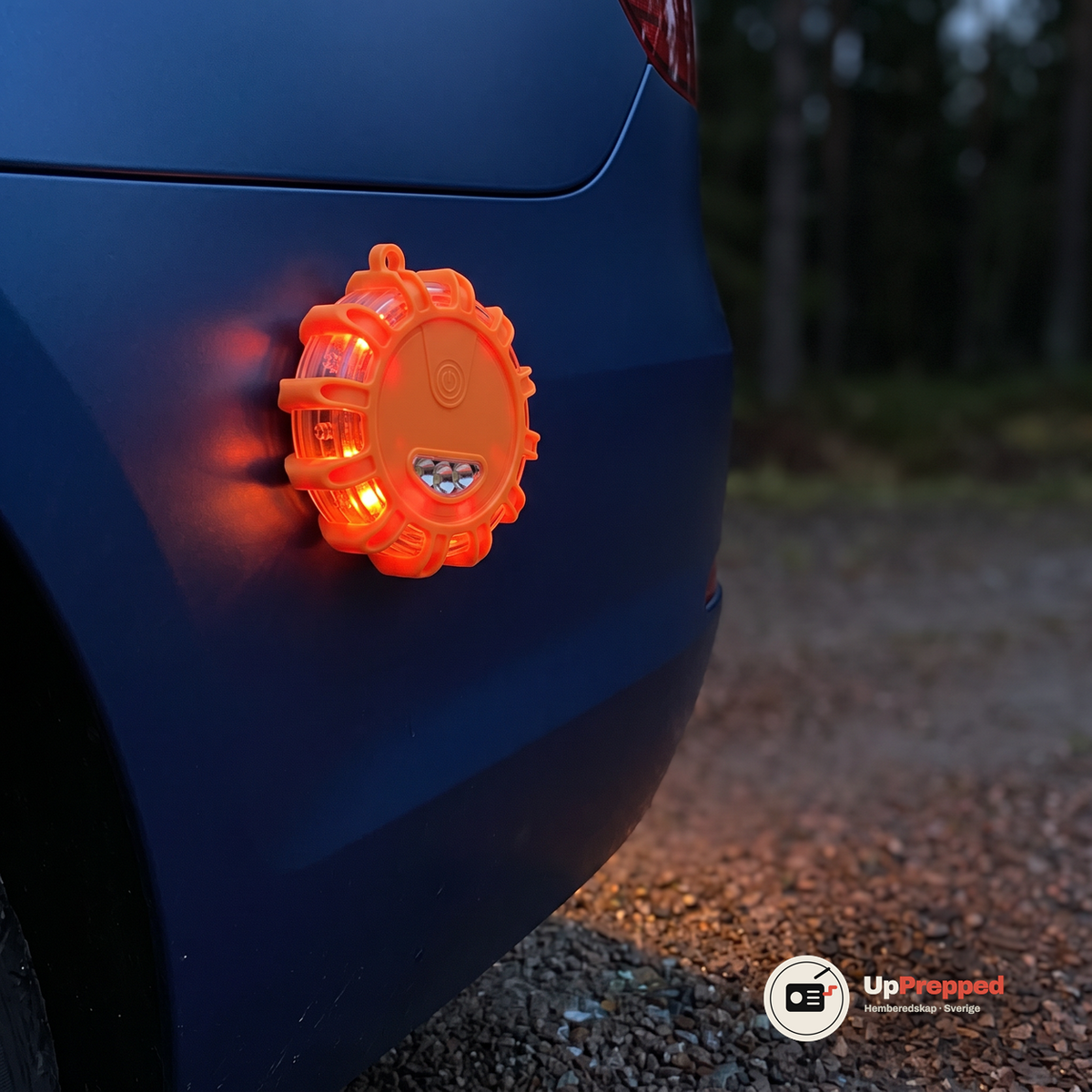 Orange varningsljus fäst med magnet på ett blått bilskärm i skymningen med röd-orange ljus