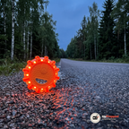 Orange varningsljus med lysande röd-orange lysdioder på grusaxeln vid en svensk landsväg i skymningen